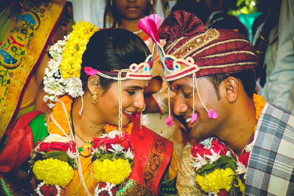 Smiling couple in colorful traditional attire during a vibrant Indian wedding ceremony.