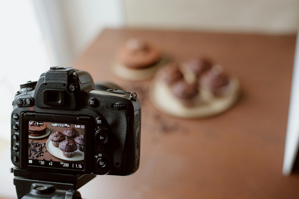 Photographing chocolate muffins using a DSLR camera in a cozy indoor setup.