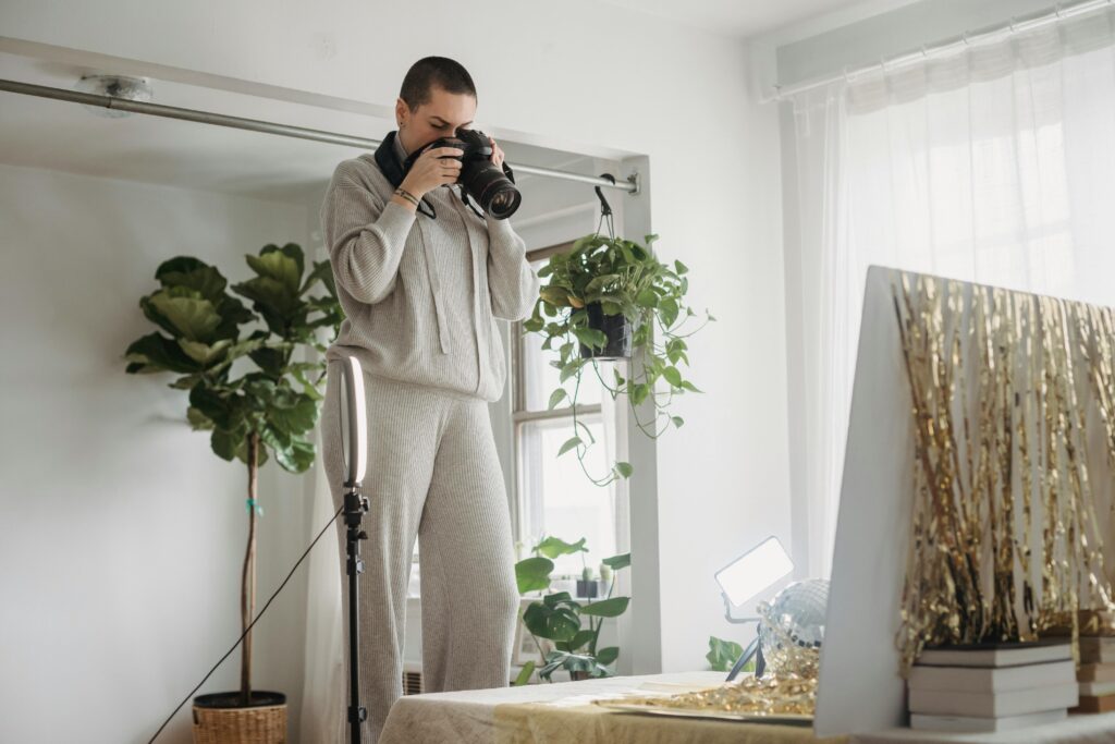 Low angle of professional photographer taking photos of party ball and tinsel in apartment
